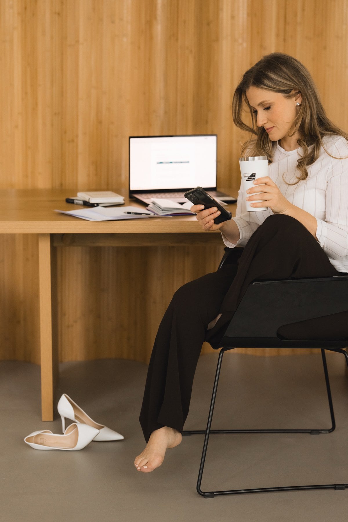 Anna Susarenco working late, shoes off, phone in hand